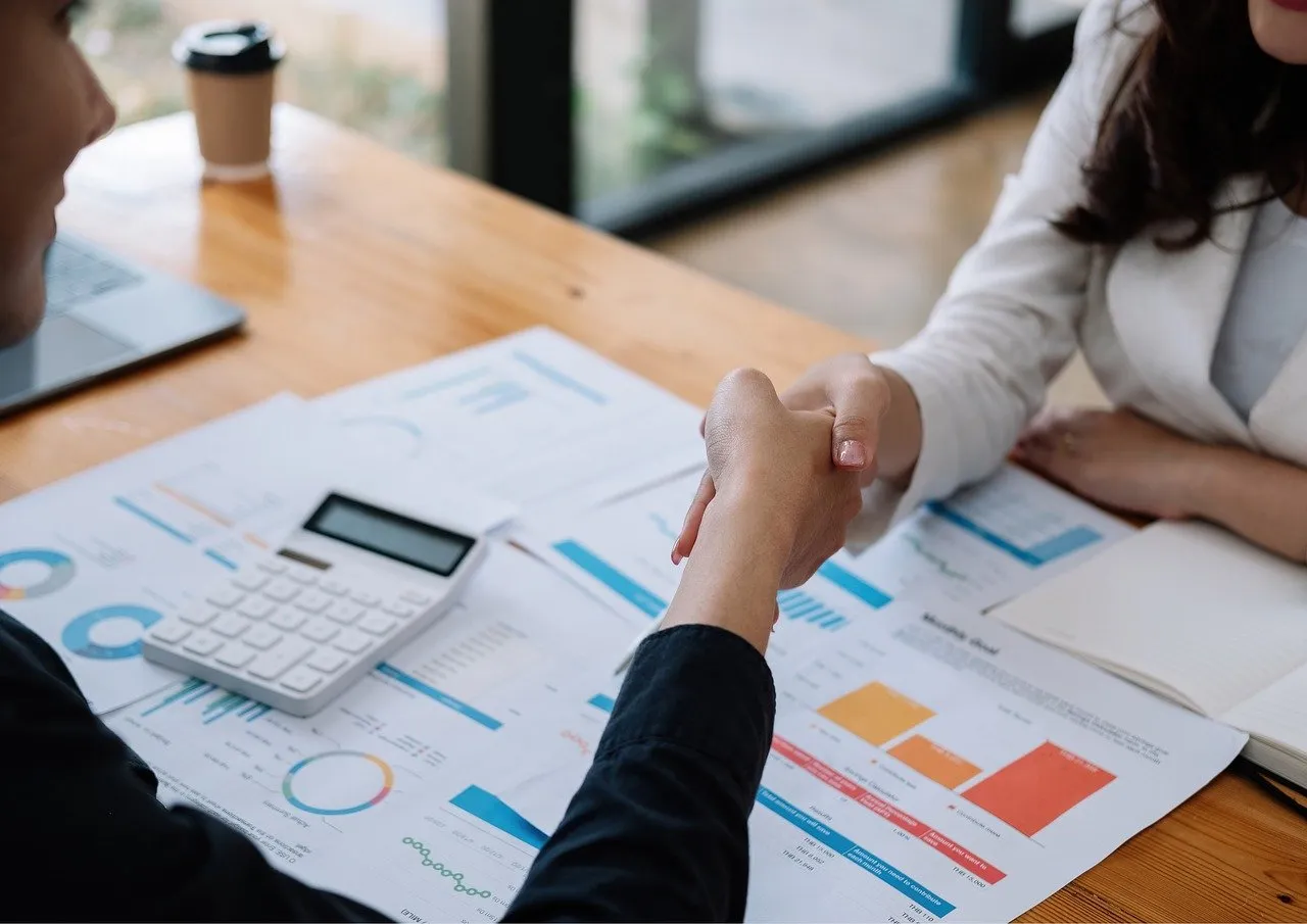 Uma mulher e um homem apertando a mão, sinalizando que o negocio foi positivo